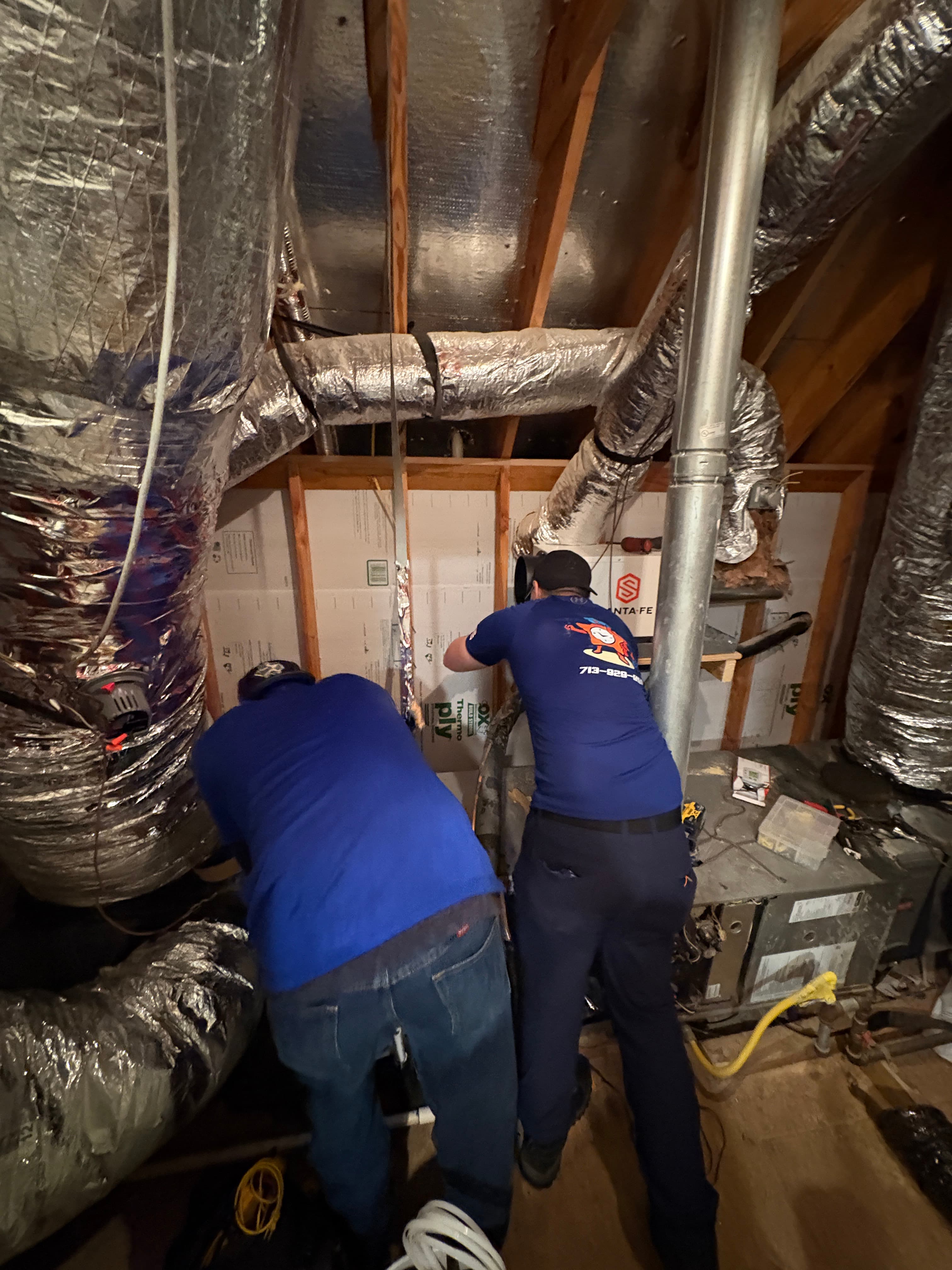 Two Air Star Now technicians running ductwork in a tight attic space